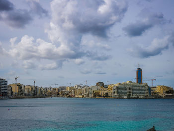 Buildings in city against cloudy sky