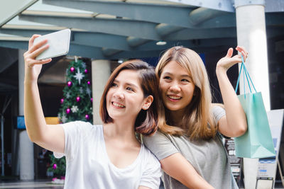 Portrait of a smiling young woman using phone