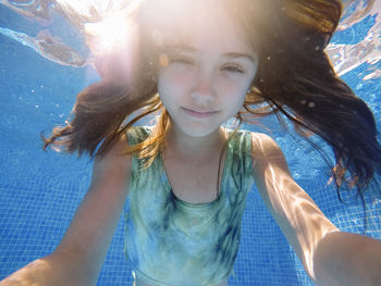 Girl with long hair swimming underwater in pool