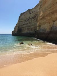 Rock formations on beach against sky