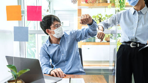 Male and female businessperson giving elbow bump at office