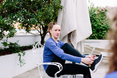 Portrait of woman sitting on seat against trees