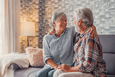 Portrait of smiling couple sitting on sofa at home