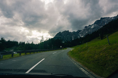 Road seen through car windshield against sky