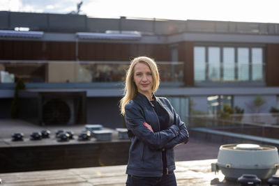 Portrait of young woman standing against building