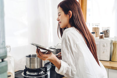 Side view of young woman preparing food at home