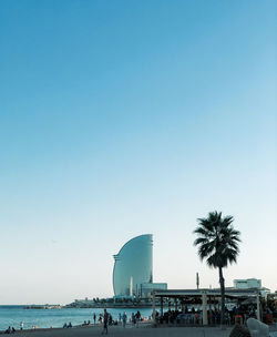 People on beach against clear blue sky