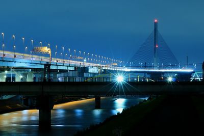Illuminated bridge against clear sky at night