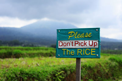 Information sign on field against sky