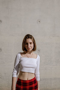 Portrait of a beautiful young woman standing against wall