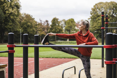 Young sportswoman doing stretching exercise in front of horizontal bar