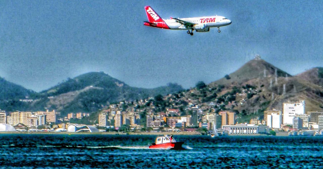 AIRPLANE FLYING OVER BUILDINGS IN CITY