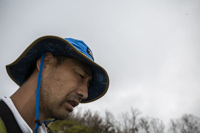 Portrait of young man looking away against sky