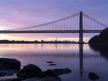 George washington bridge over hudson river against purple sky during sunset