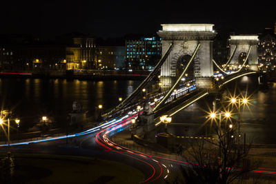 Light trails on suspension bridge in city at night