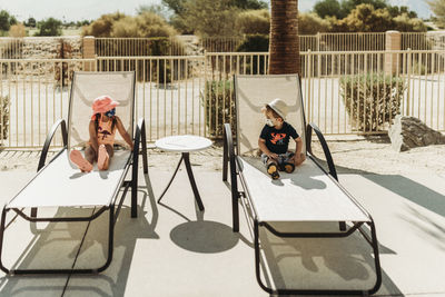 Young toddler siblings with mask on sitting by pool in palm springs