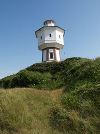 Low angle view of lighthouse on field against clear sky