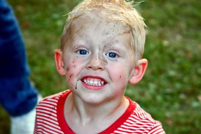 Close-up portrait of boy with messy face standing on field