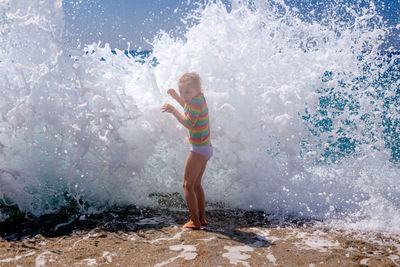 Full length of girl standing against wave