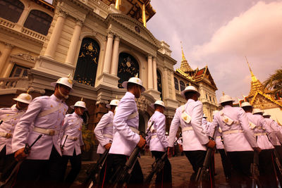 Army soldiers marching by historic building during sunset