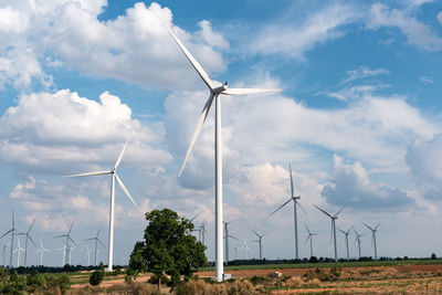 Windmills on field against sky