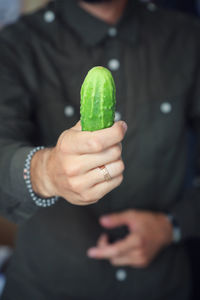 Close-up of man holding a cucumber