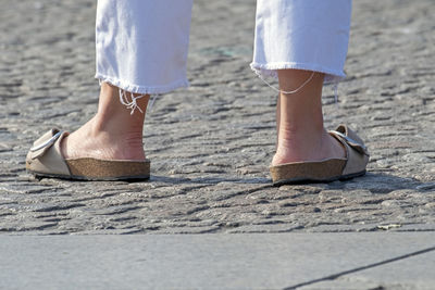 Female feet in sandals on a street pavement person