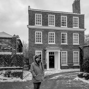 Woman photographing with umbrella standing in front of house