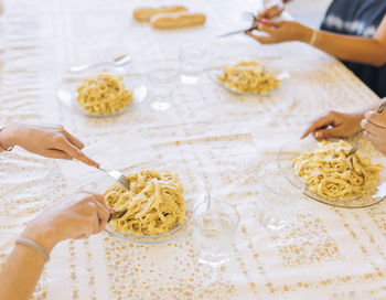 Friends sitting at table eating cheese with truffle pasta