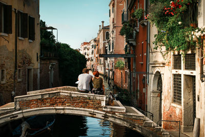 Rear view of canal amidst buildings in city