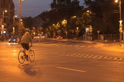 Man riding bicycle on city street at night