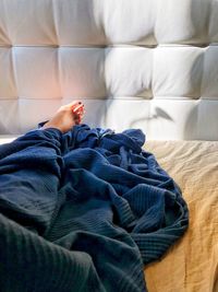 Low section of woman relaxing on bed at home