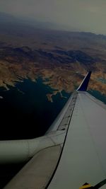 Aerial view of airplane wing over landscape against sky