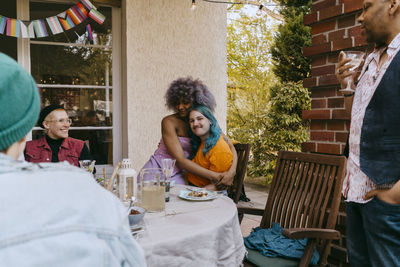 Side view of smiling friends sitting on table