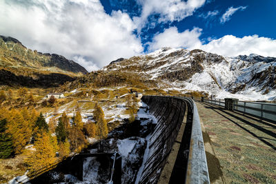 Scenic view of the path on the dam and snowcapped mountains on the background 