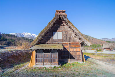 Abandoned built structure on field against clear blue sky