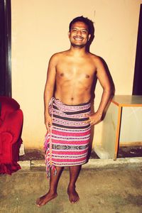 Portrait of smiling young man standing against wall