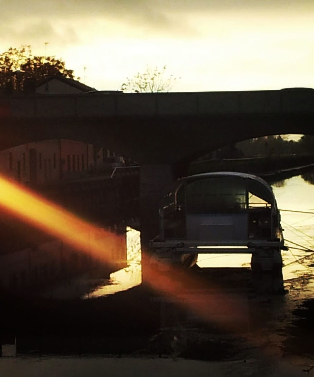 reflection, light, sunset, evening, sky, sunlight, darkness, transportation, architecture, nature, mode of transportation, cloud, no people, water, built structure, vehicle, dusk, motor vehicle, outdoors, lighting, car