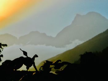 Silhouette of mountain range against cloudy sky