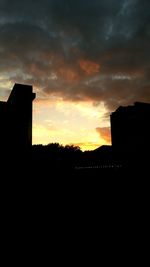 Silhouette of built structures against dramatic sky