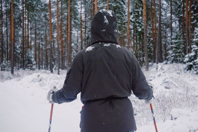 Rear view of man standing in snow covered forest