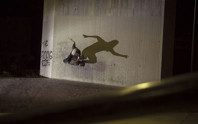 Man skateboarding on wall at playground during night