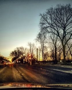 Road by silhouette trees against sky at night