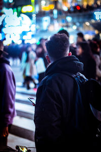 Man walking on road in illuminated city at night