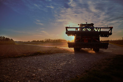 Lifeguard hut on agricultural field against sky during sunset