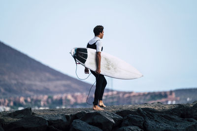 Man standing on rock against sky