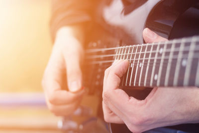 Midsection of person playing guitar outdoors