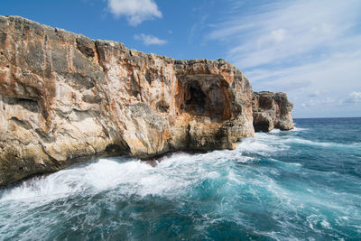 Rock formation on sea shore against sky