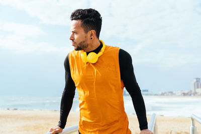 Man with headphones standing at beach