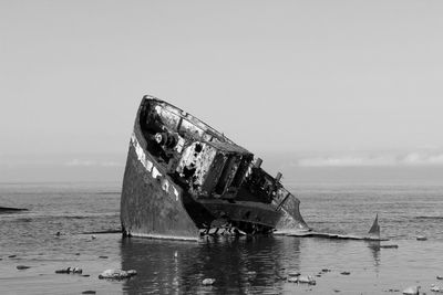 Abandoned boat on sea against sky